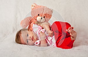 Baby girly lying in front of a pink teddie photo