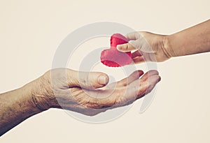 Baby giving a red heart to an old