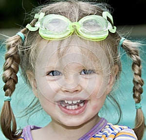 Baby in goggles swim pool.