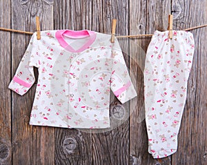 Baby goods hanging on the clothesline. Baby blouse and pants sliders on the clothespin on the rope