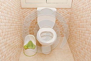 Baby green potty in toilet. Hygiene. Children`s toilet. Children`s pad, cover, toilet seat. The child goes to an adult toilet