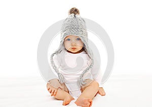 Baby in grey knitted hat on white background