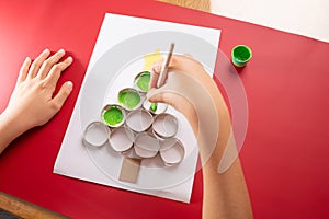 baby hand drawing Christmas tree, paper craft made of empty toilet paper roll