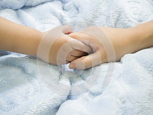 Baby hand gently holding adult's finger