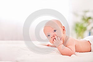 A baby with a hand in his mouth. teething in children. sucking reflex. hungry little baby. lying on his stomach on their own holds