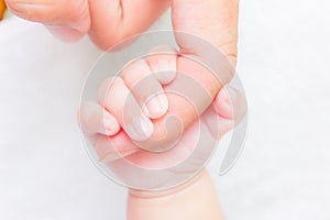 Baby hand holding adult finger
