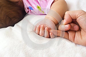 Baby hand holding mother finger.