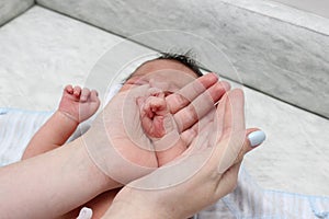 Baby hand in mother hands. Tiny Newborn Baby`s feet on female Shaped hands closeup. Mom and her Child