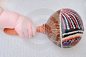 Baby hand and percussion musical instrument, close-up. Children fingers and an object on a white background