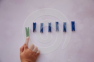 Baby hand picks one stationery clothespins. Curiosity and be different concept. Copy space