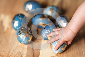 Baby hand touching blue easter eggs decorated gold patel on wood background photo