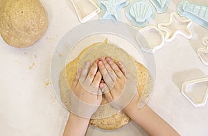 Baby hands with dough for making homemade cookies.