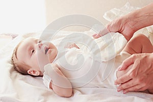 Baby and hands of mother with a baby nappy, indoors, blurred background