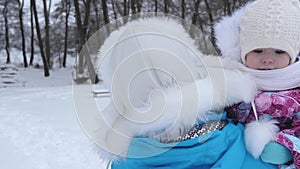 Baby on hands of my mother walks in winter on white snow on frosty day. Mother with child for walk in nature. Christmas