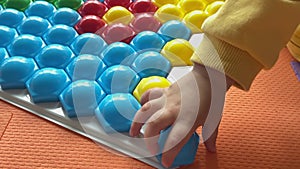 baby hands play colorful mosaic tiles put plastic piece into white slot close-up