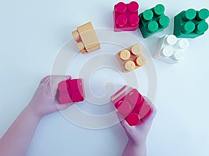 Baby hands playing colorful with plasticconstruction blocks on white background