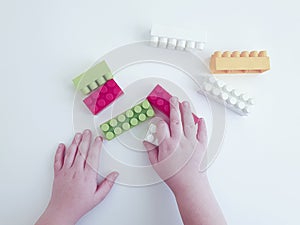 Baby hands playing with plasticconstruction blocks on white background