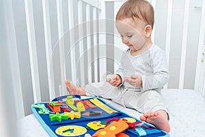 Baby happily plays with felt board in crib