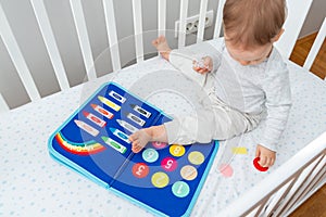 Baby happily plays with felt board in crib