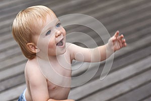 Baby, happy on floor outdoor for development with relax, curiosity and early childhood in backyard of home. Toddler