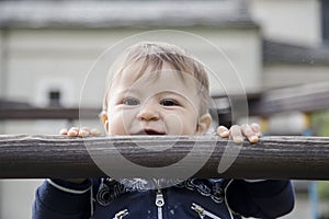 Baby having fun while hanging on wooden bar