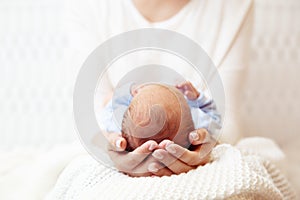 Baby Head in Mother Hands. Mum holding Newborn Boy lying on White Blanket. Infant Health Care and Development. Child Birth