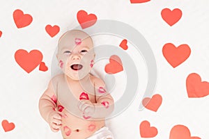 Baby among hearts and with kisses from red lipstick, the concept of love and Valentine`s day