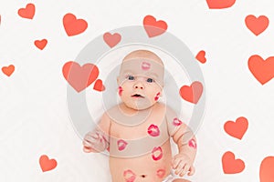 Baby among hearts and with kisses from red lipstick, the concept of love and Valentine`s day