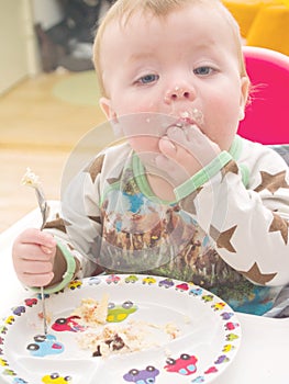 Baby on his first birthday eating cake