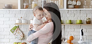 Baby and his mommy hugging at kitchen, panorama