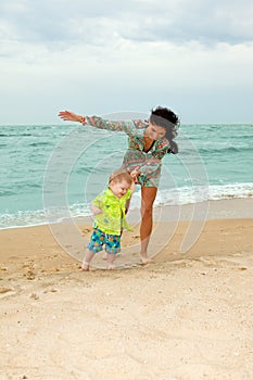 Baby and his mother walking on the beach