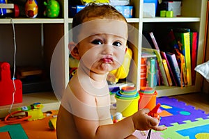 Baby in his room making funny faces of duck face