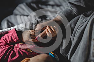 Baby hold her mothers hand while sleep close up on hand of small infant baby girl holding thumb of her mother unknown while sleep