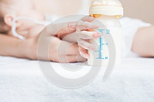 Baby holding a baby bottle with breast milk