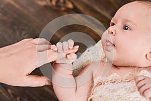 Baby holding finger of woman.