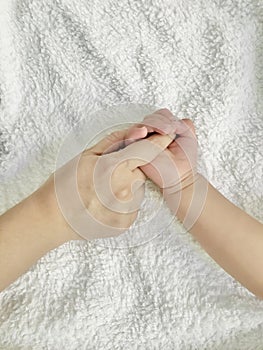 Baby holding it`s mothers finger. Vertical photo image.