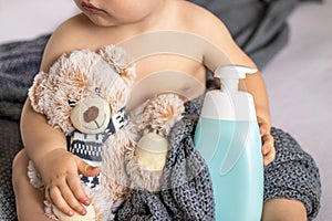 baby holding shampoo shower gel bottle soft toy teddy bear