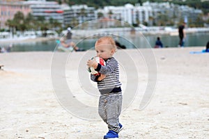 Baby Holding a Soccer Ball on Sand at the Beach