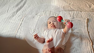 Baby holds a toy while lies on bed