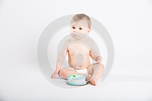 Baby with Icing on His Mouth Sitting Next to Cake