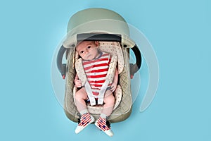 Baby in infant car seat on blue studio background. Child in the clothes of the red and white USA flag