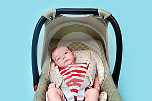 Baby in infant car seat on blue studio background. Child in the clothes of the red and white USA flag