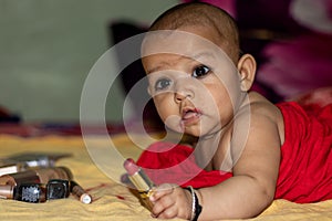 Baby infant cute holding lipstick with blurred background