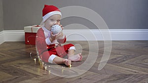 baby infant kid red Santa costume hat plying Christmas lights wooden floor home