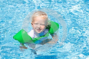 Baby with inflatable armbands in swimming pool.