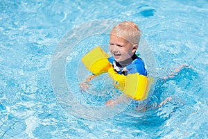 Baby with inflatable armbands in swimming pool