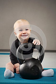 Baby with kettlebell. Child at the gym