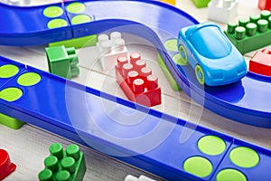 Baby kid toys background. Toy car  plastic road and colorful blocks on white wooden background