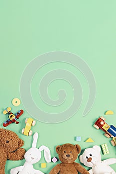 Baby kids toys background. Teddy bears, wooden train, toy cars, colorful blocks on light green background. Top view