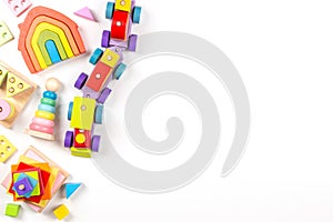 Baby kids toys background. Top view to wooden toy train, wood stacking pyramid tower and colorful wood bricks on white